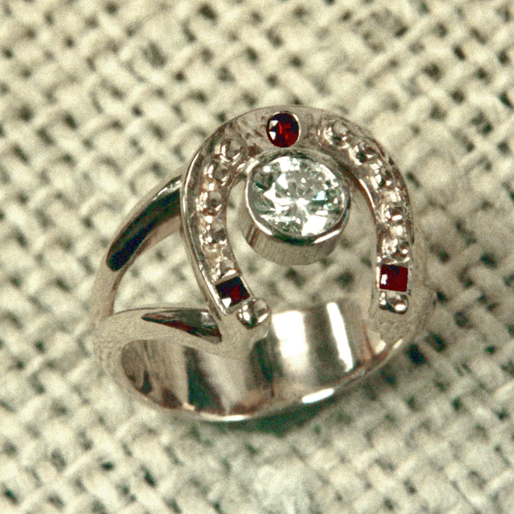 Picture of a custom horseshoe engagement ring with diamond main stone and rubies