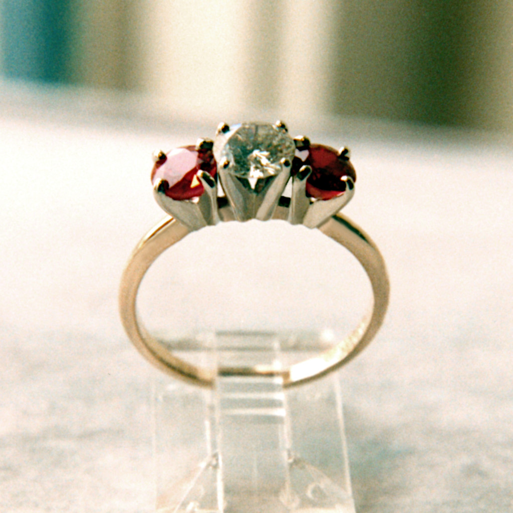 Picture of a 14 karat 2 tone ring, has a diamond main with 2 ruby side stones, all in prongs