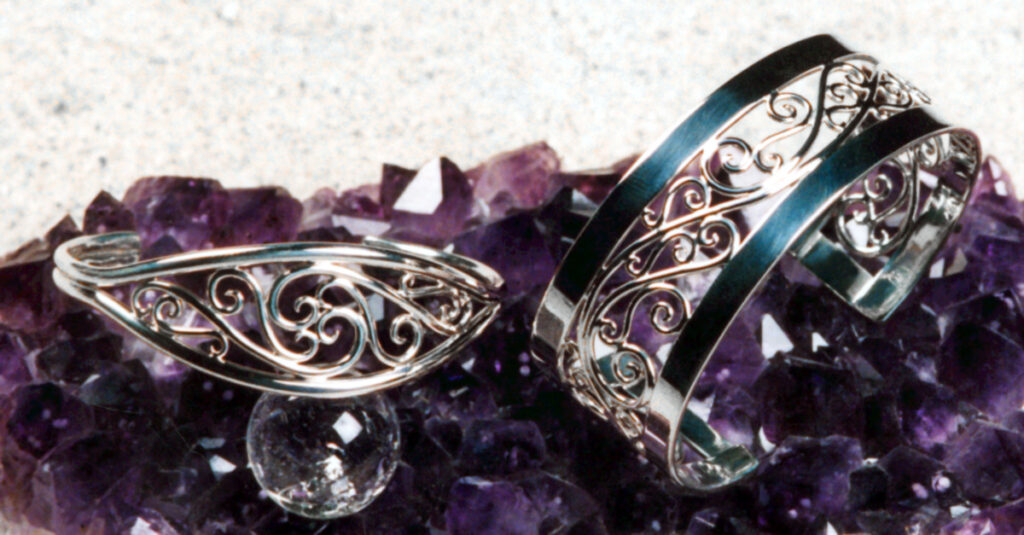 Picture of two sterling scroll cuff bracelets on an Amethyst cluster